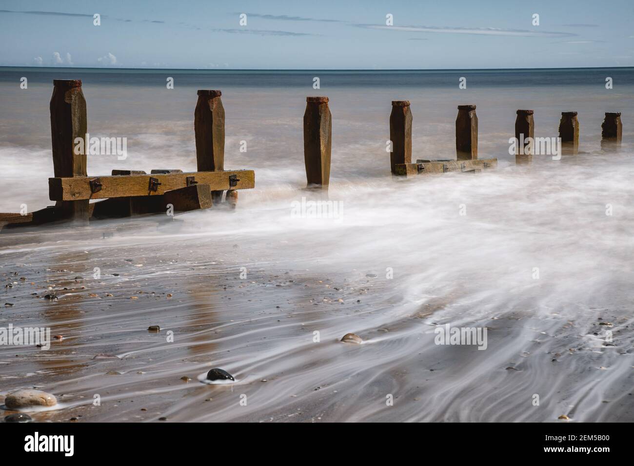 Front de mer Hornsea avec plage, marée ondule autour des galets et des gémins de mer Banque D'Images