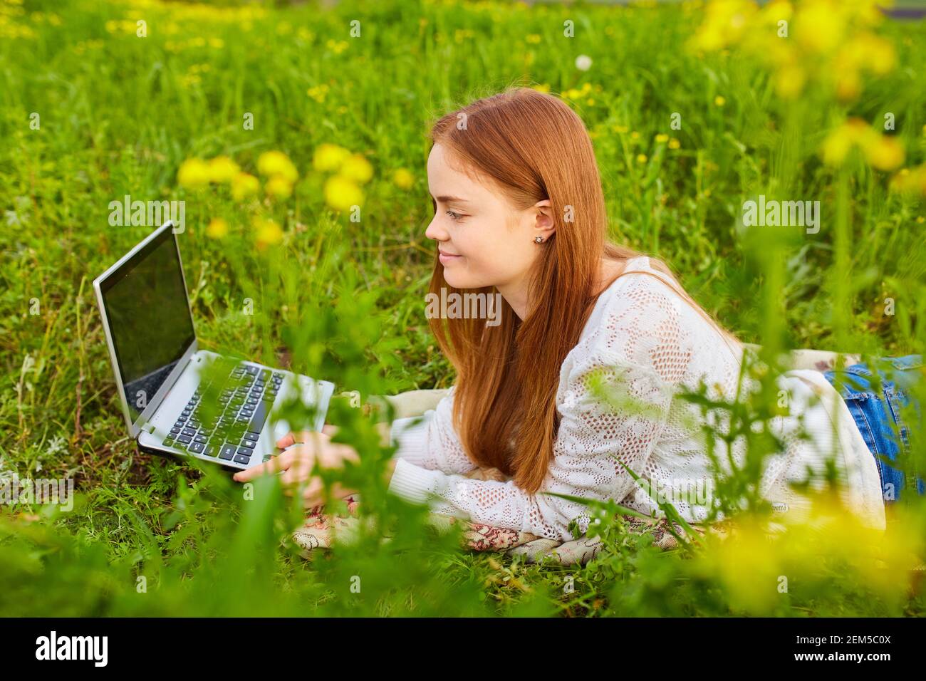 fille travaillant dans la nature avec un ordinateur portable couché sur ...