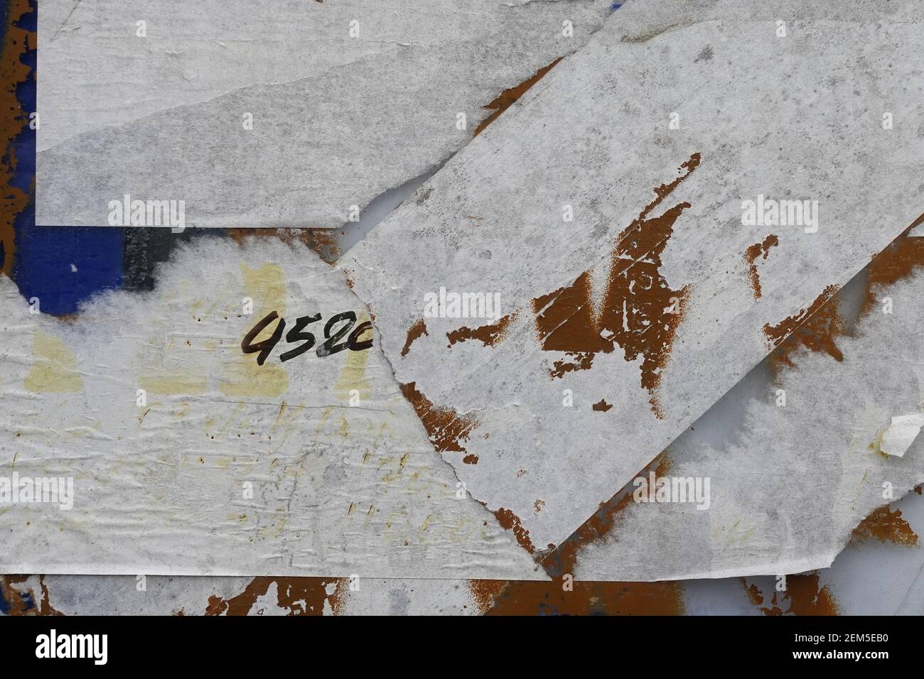 Des autocollants en papier déchirés et de la peinture écaillée grégent la texture de l'arrière-plan. Banque D'Images