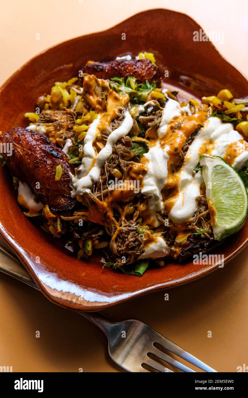 Bol de riz jamaïcain au poulet jerk avec des plantains sucrés et chauds sauce Banque D'Images