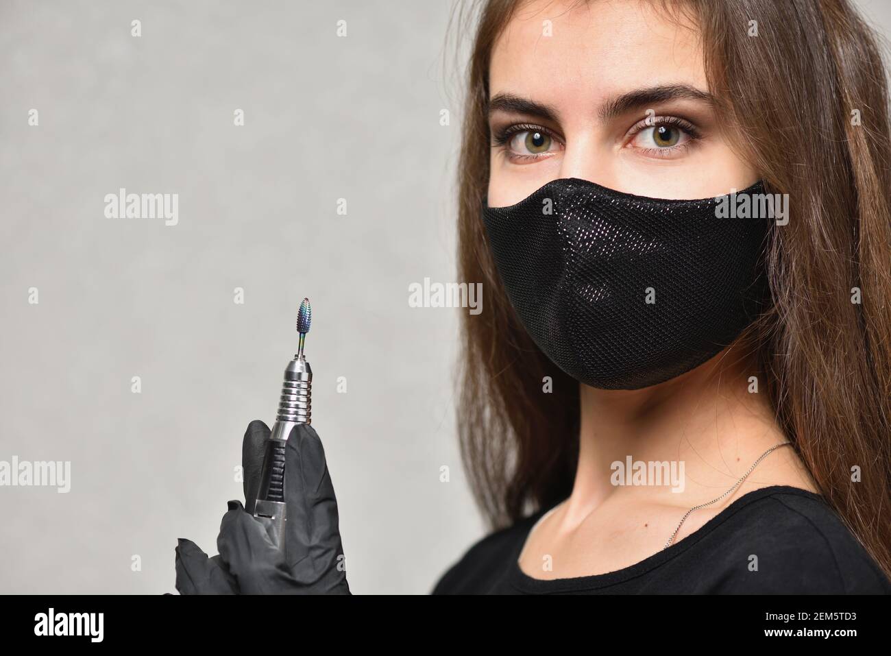 Jeune femme caucasienne maître de manucure posant avec lime à ongles électrique, concept de soin des ongles Banque D'Images