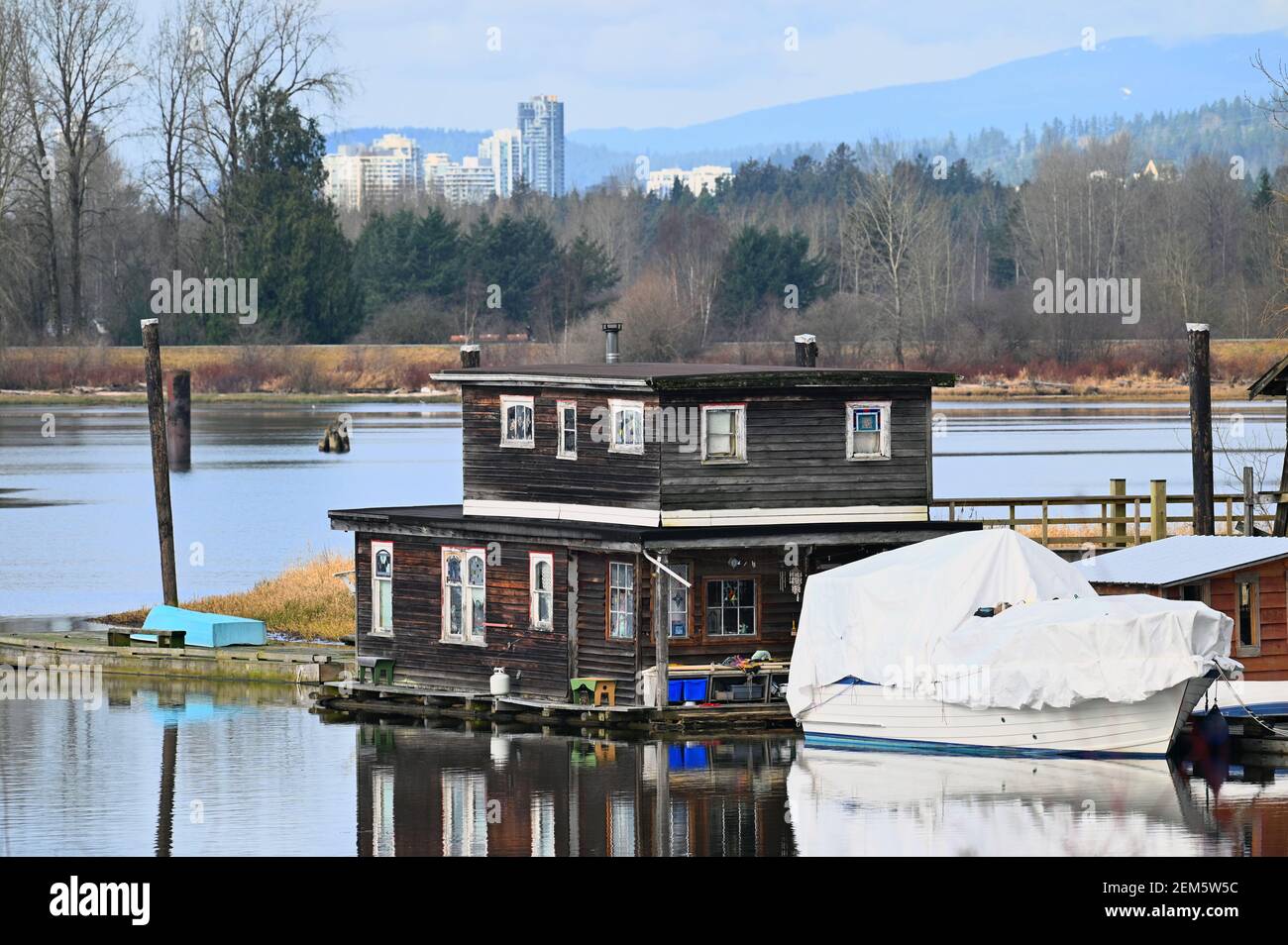 Une péniche aménagée sur Pitt River Pitt avec des gratte-ciel en arrière-plan. Pitt Meadows, B. C., Canada Banque D'Images