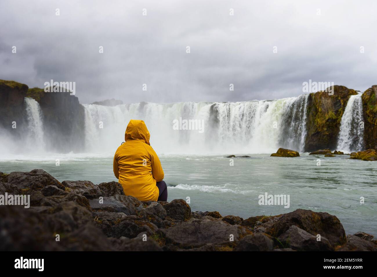 Tourisme dans une veste jaune se relaxant à la cascade Godafoss en Islande Banque D'Images