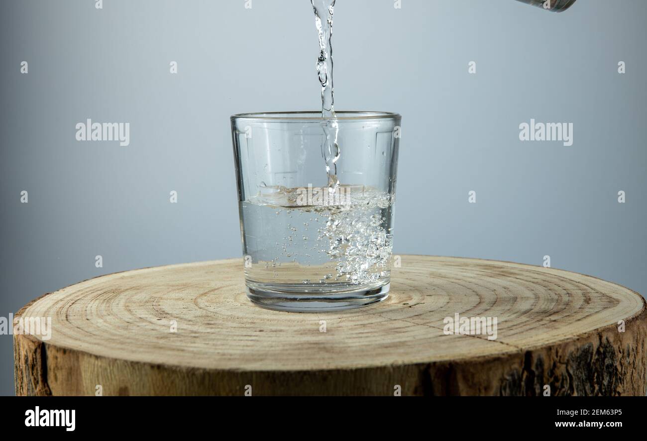 Verser de l'eau dans un verre sur fond blanc Banque D'Images