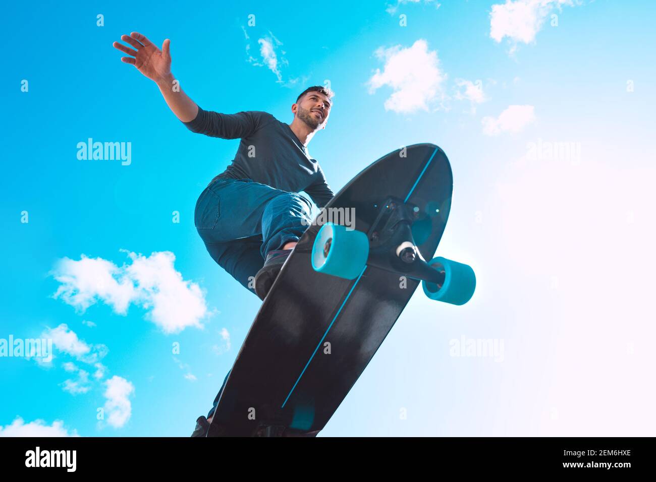 Skateboarder en action, faire le tour. Sports d'été. Fond bleu ciel. Banque D'Images