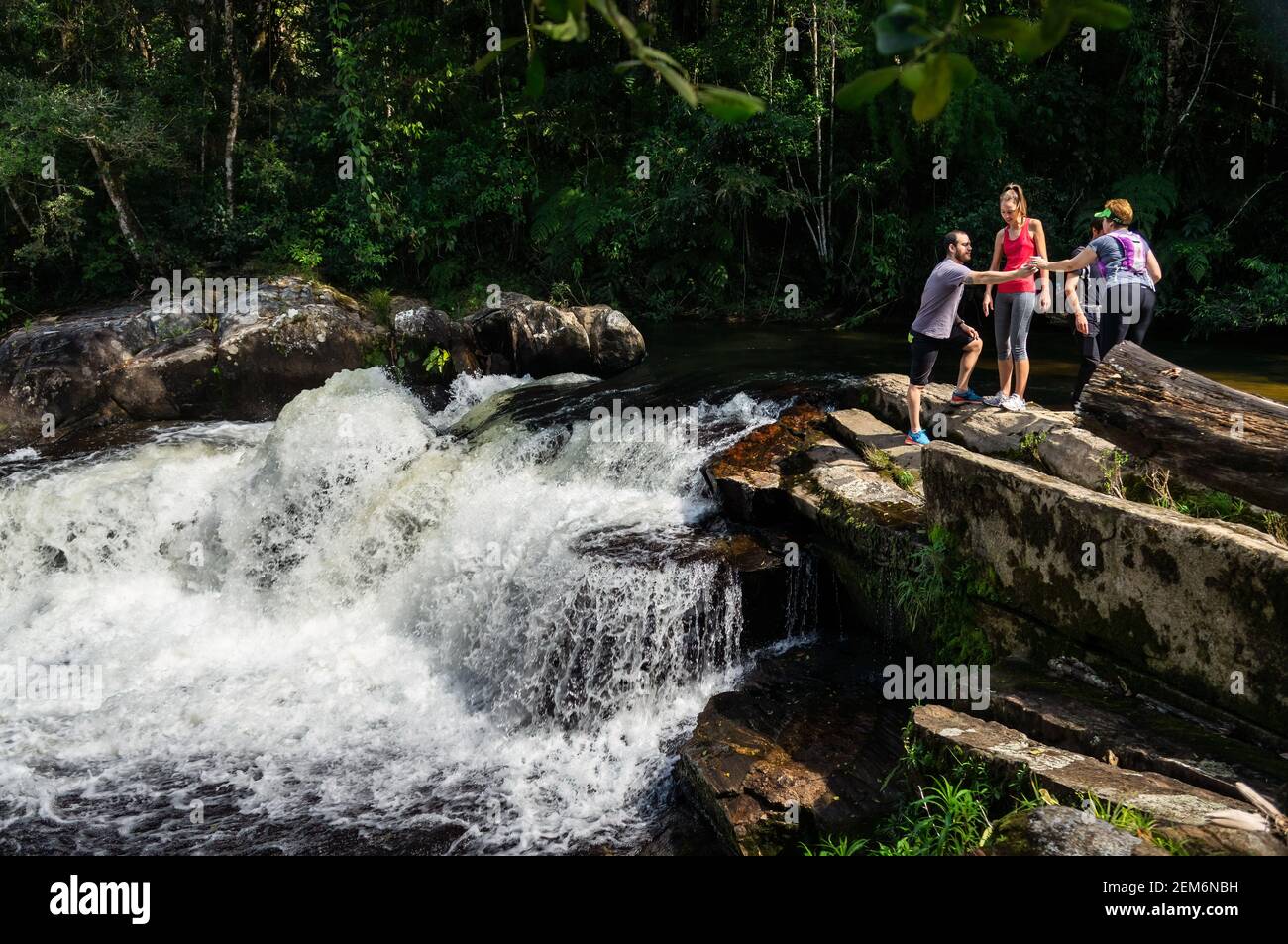 Fort courant d'eau cristalline de la rivière Paraibuna qui coule entre les formations rocheuses avec quelques randonneurs à proximité dans le parc de domaine de Serra do Mar. Banque D'Images