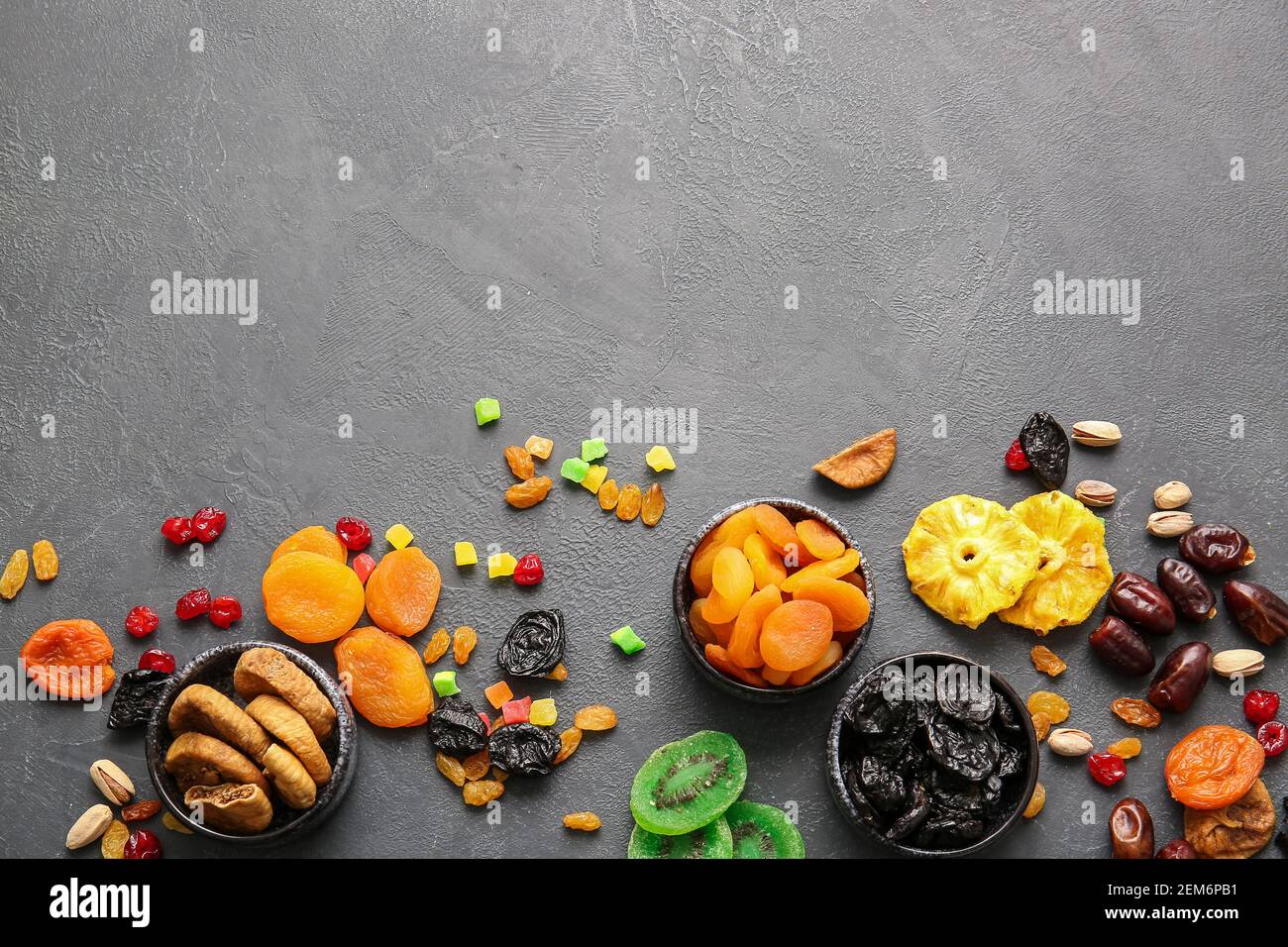 Bols avec différents fruits secs sur fond sombre Banque D'Images