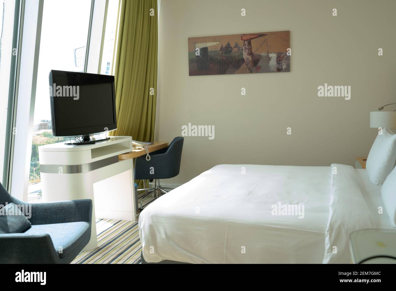 Décoration moderne et confortable dans les chambres mansardées, lumière naturelle et lumineuse à travers la fenêtre, lit king-size, chaises, télévision et table avec lampe Banque D'Images