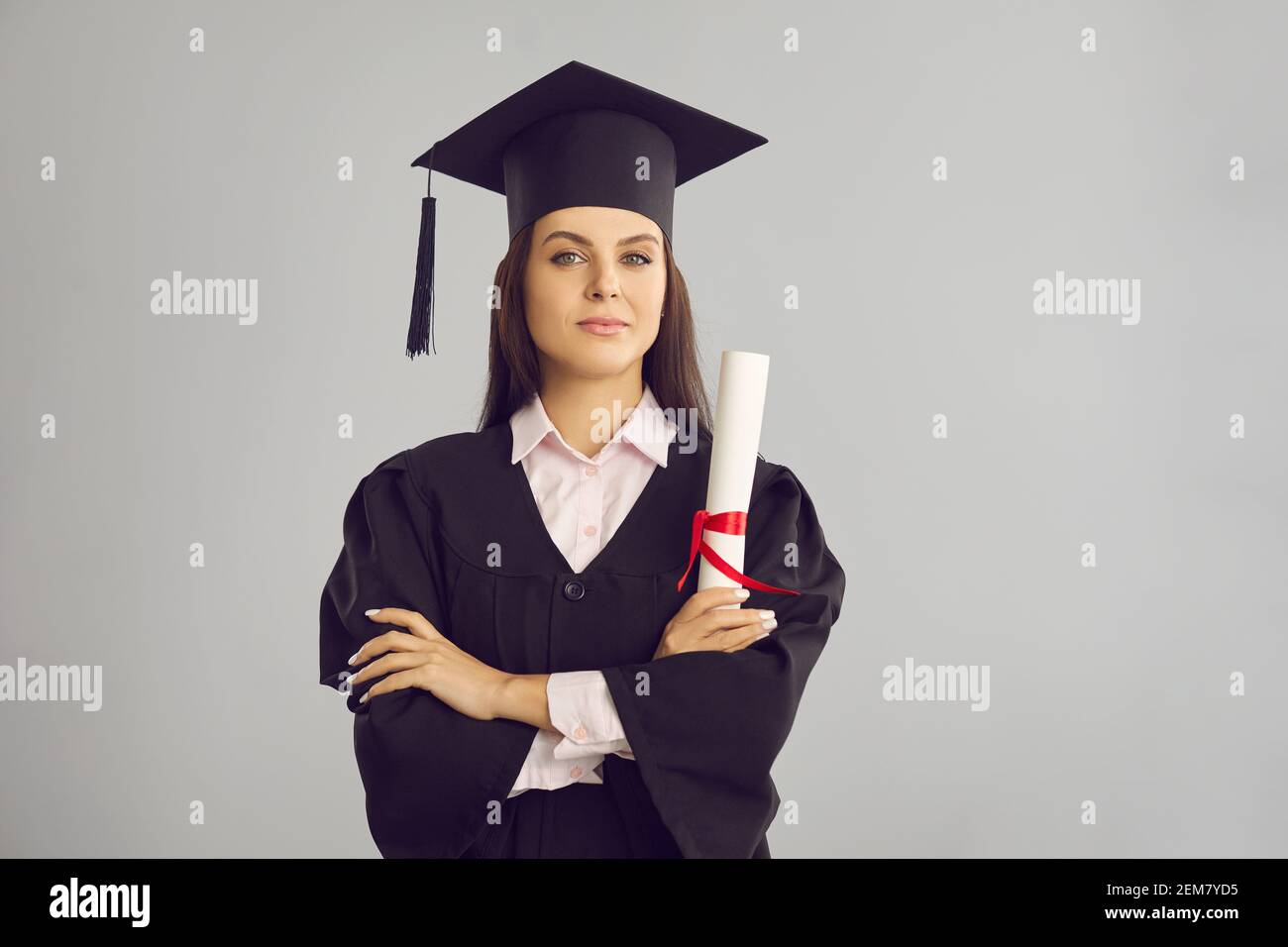 Femme diplômée de l'université dans le bonet traditionnel et le manteau debout avec diplôme en main Banque D'Images