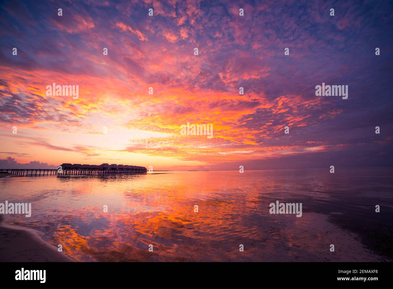 Incroyable coucher de ciel et la réflexion sur une mer calme, plage de luxe Maldives paysage de bungalows sur pilotis. Les paysages exotiques de l'été et de vacances Maison de vacances Banque D'Images