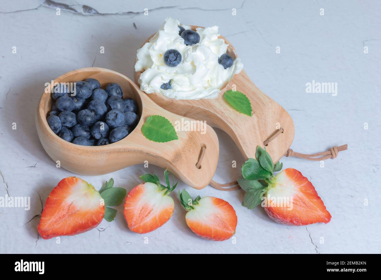 Bleuets frais et fraises à la crème dans une tasse en bois. Concept de thèse naturelle. Photo de haute qualité Banque D'Images