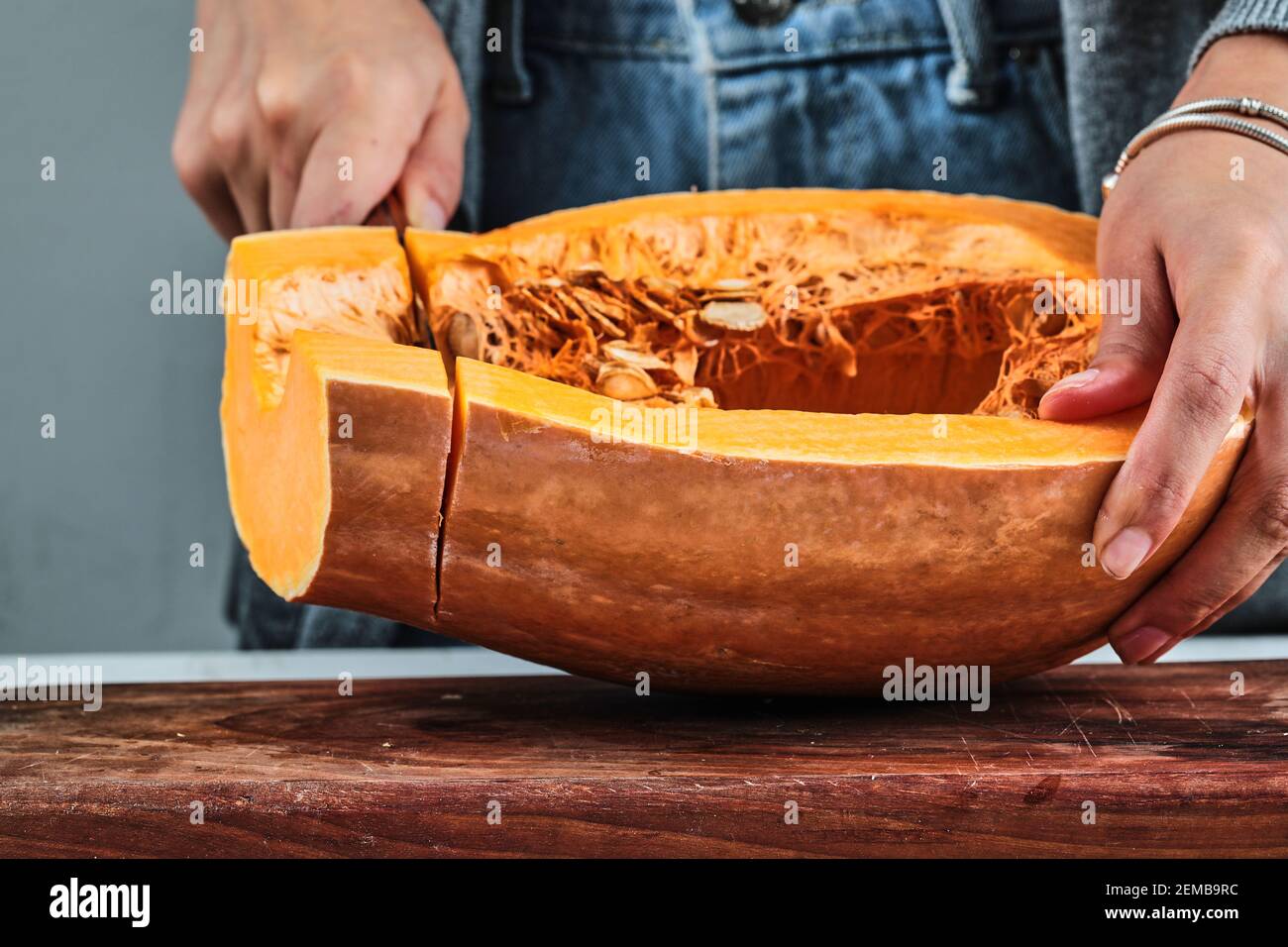 Une femme coupe à la main une tranche de citrouille avec un couteau sur la planche de bois Banque D'Images