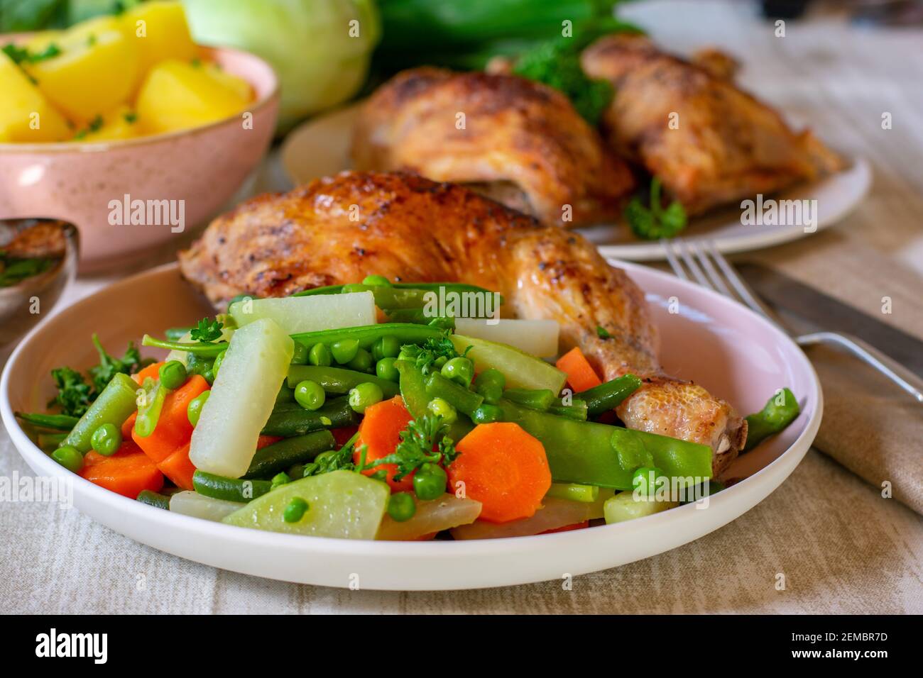 cuisse de poulet grillée avec légumes de printemps servis sur une assiette sur la table du dîner Banque D'Images