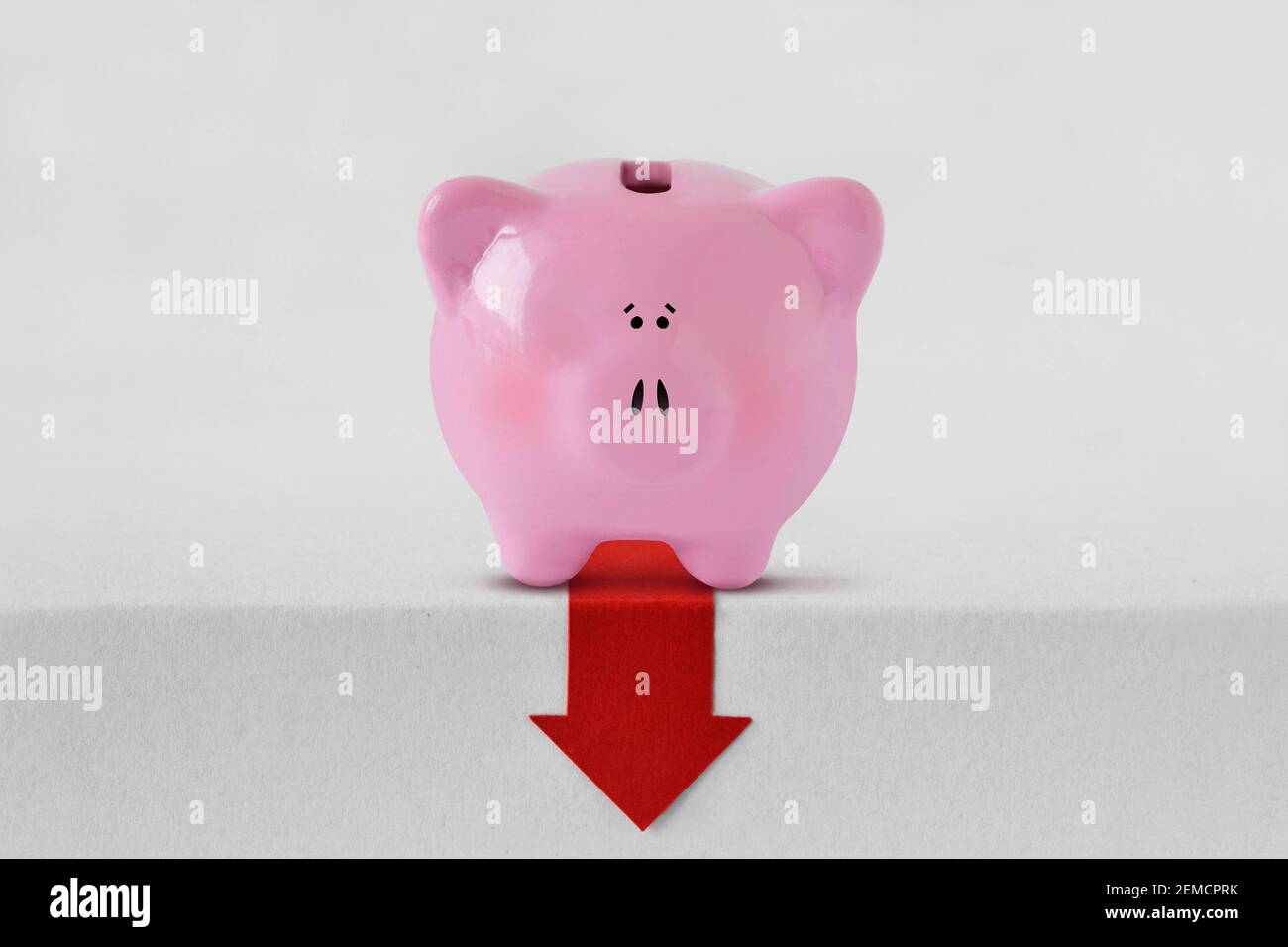 Piggy banque avec flèche rouge vers le bas - crise financière et concept de perte d'argent Banque D'Images