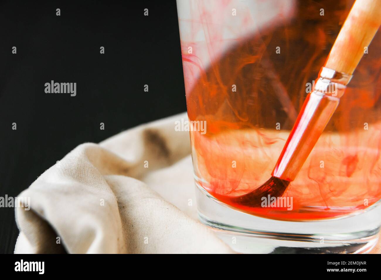 Brosses artistiques souillées dans la peinture trempez dans un verre avec eau Banque D'Images