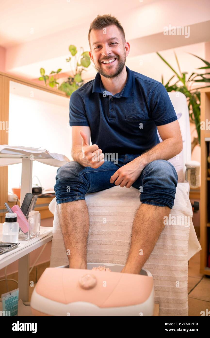 Jeune homme dans un salon de pédicure assis avec ses pieds sombré dans une  baignoire spa Photo Stock - Alamy