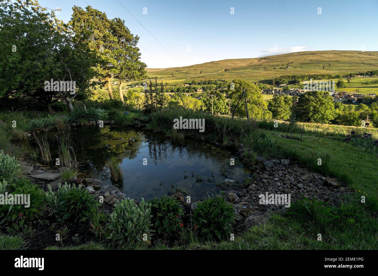 Un étang dans un jardin de campagne, avec le soleil des Pennines du Nord en arrière-plan Banque D'Images