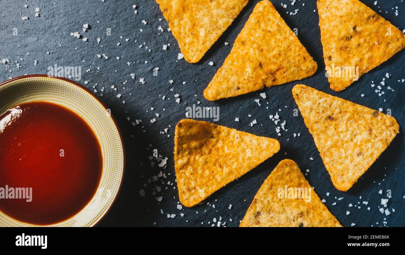 la nourriture. Éclats de tortilla en forme de triangle jaune sur noir. Base mexicaine de collations salées de maïs. Délicieux nachos pour hors-d'œuvre. Décoration croquante traditionnelle Banque D'Images
