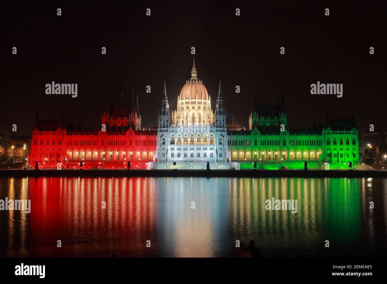La nuit, le Parlement hongrois est éclairé de couleur nationale rouge, blanc et vert sur la rive du Danube; photo en couleur. Banque D'Images