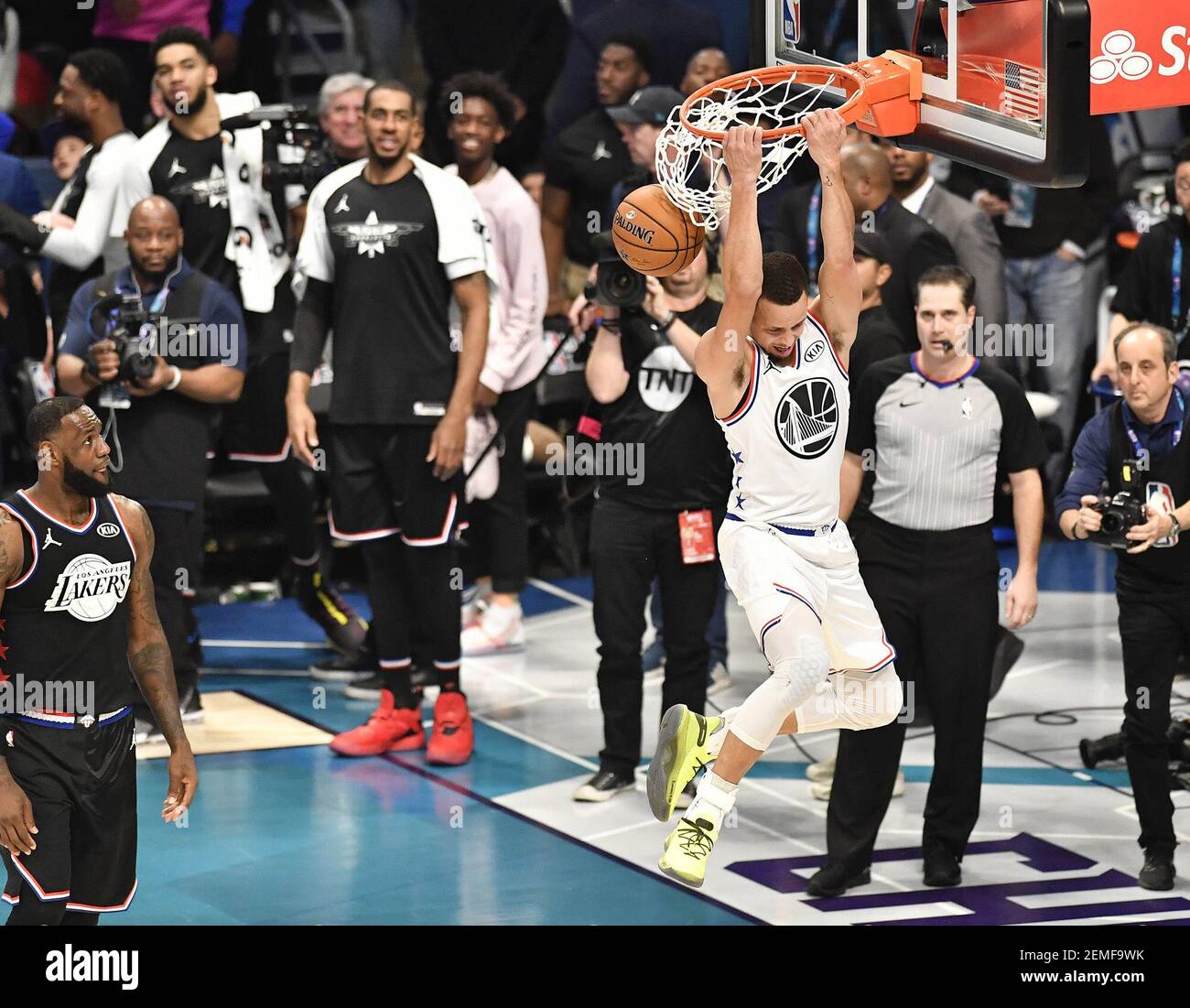 Stephen Curry de l'équipe Giannis, des Golden State Warriors, monte pour  une dunk à deux mains en marche arrière, comme LeBron James de l'équipe  LeBron, des Los Angeles Lakers, regarde pendant le