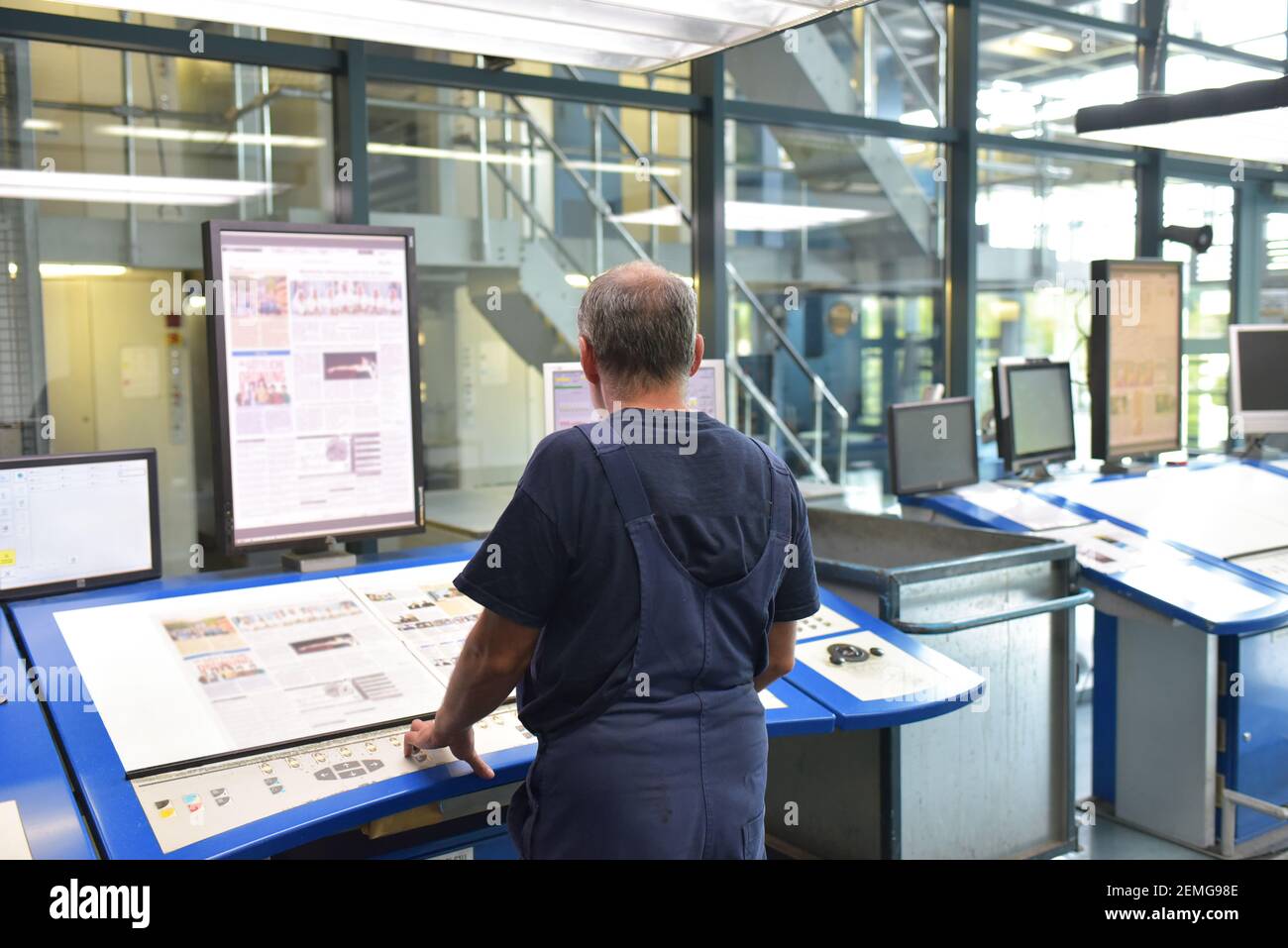 Un travailleur informatique dans une usine d'impression de journaux vérifie la mise en page Banque D'Images