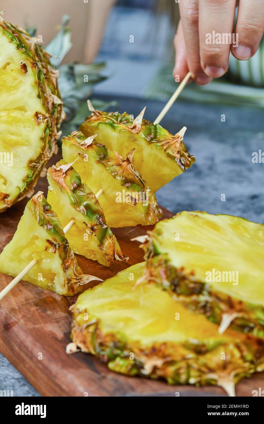 Un homme prenant une tranche d'ananas sur un panneau de bois Banque D'Images