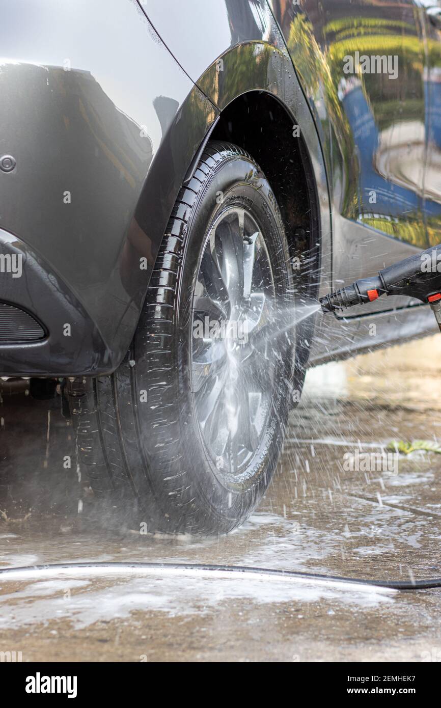 Lavage manuel de voiture avec de l'eau sous pression. Nettoyage de la partie avant de la voiture avec de l'eau haute pression. Banque D'Images