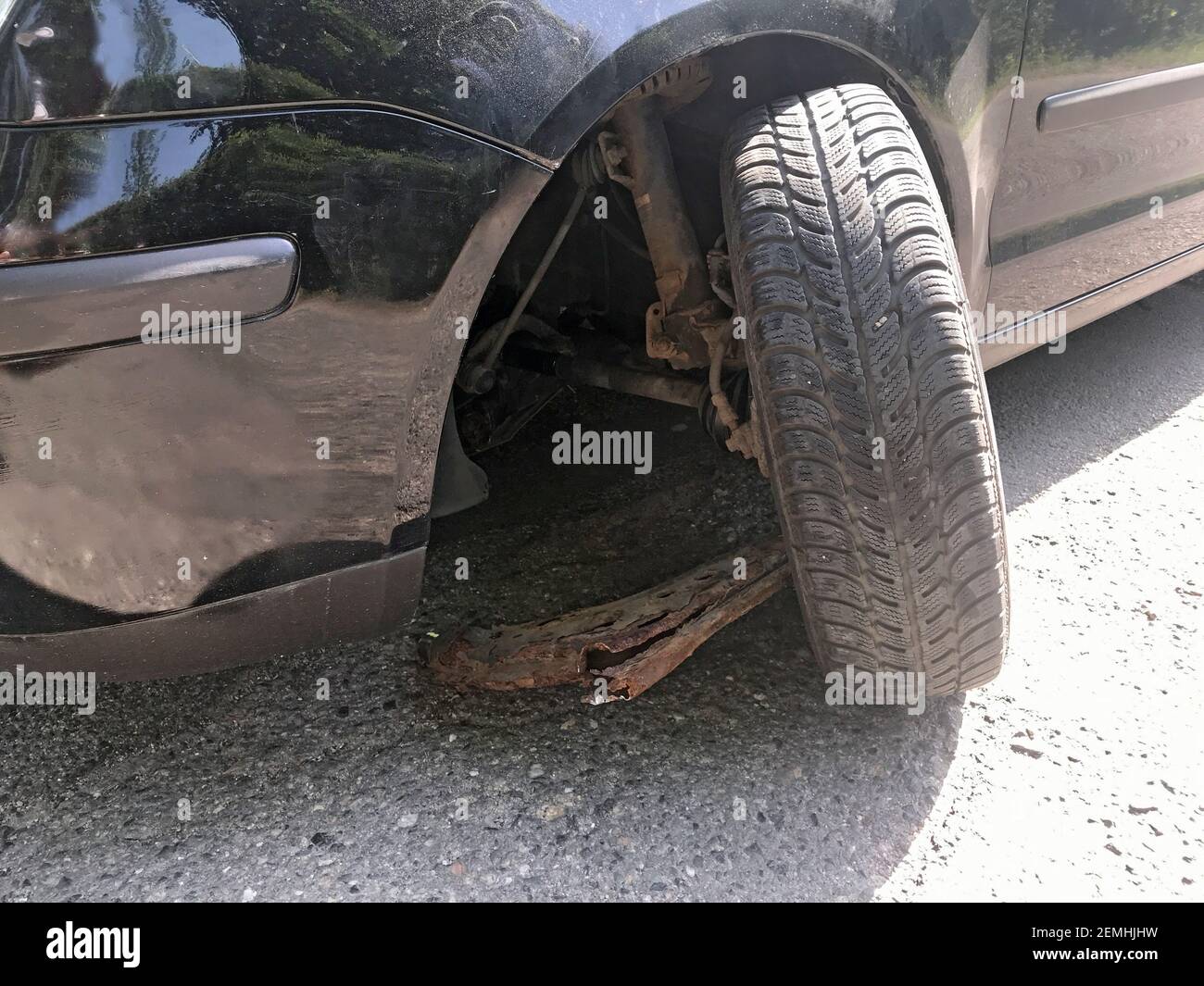 Roue endommagée d'une voiture causée par un trou dans une route rurale. Roue arrachée d'essieu corrodée sur la voiture. Banque D'Images