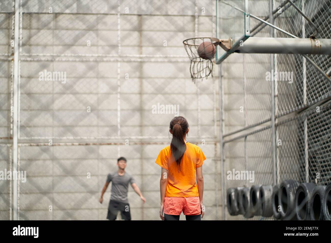 un jeune homme et une femme asiatiques jouant au basket-ball sur un terrain en plein air Banque D'Images