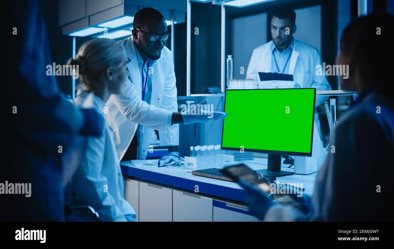 Réunion des laboratoires de recherche médicale : diverses équipes de scientifiques utilisent l'ordinateur pour montrer l'écran clé vert Chroma, discutez des innovations. Laboratoire avancé pour Banque D'Images