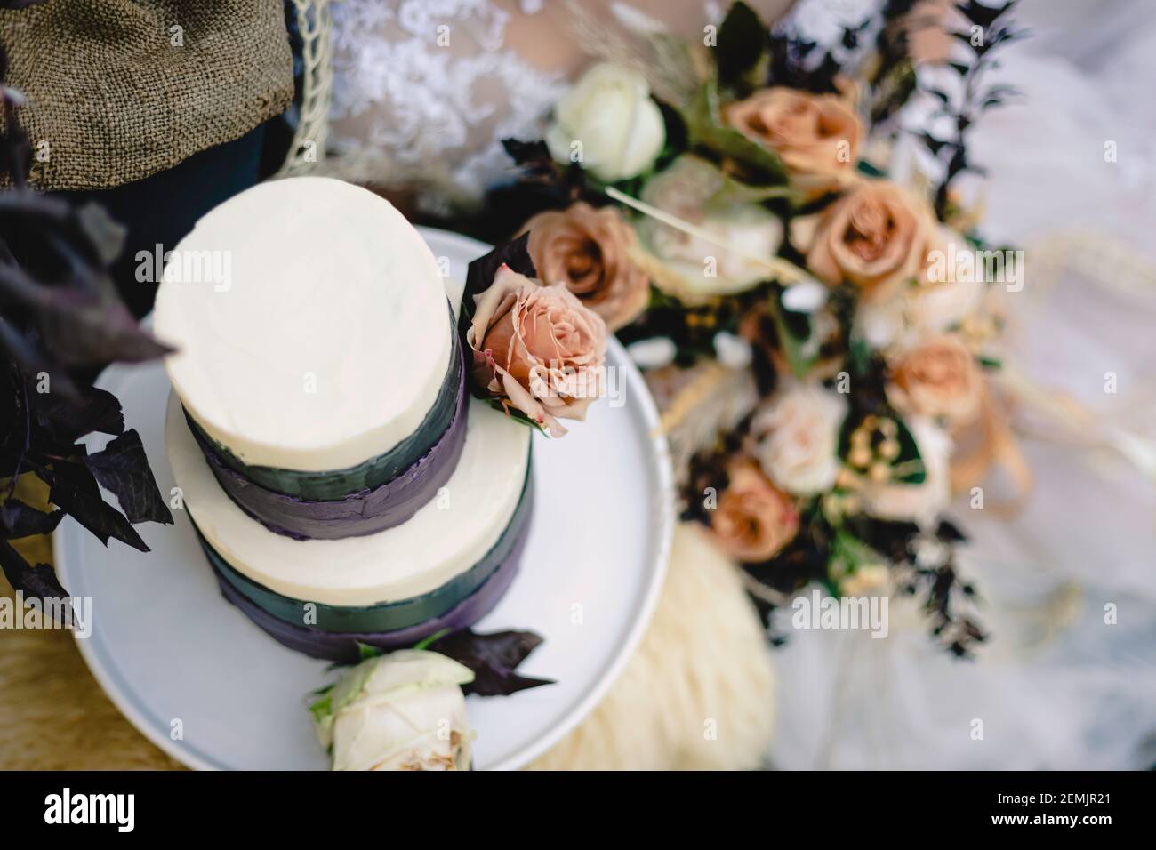 Gros plan de gâteau de mariage avec roses rose clair, ganache pourpre contre cadre rustique Banque D'Images