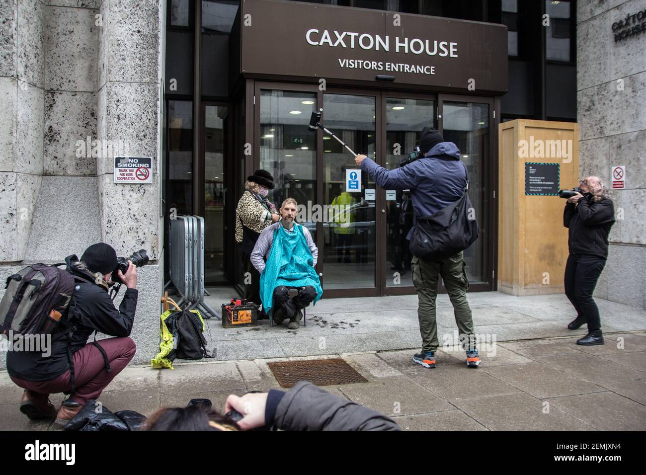 Londres, Royaume-Uni. 25 février 2021. La scène est presque prête à Caxton House, à Westminster, alors que le Dr Larch Maxey, 48 ans, a été expulsé d'un TUNNEL SOUTERRAIN STOP-HS2 à Euston Square il y a deux jours, se réunit avec d'autres activistes environnementaux sous les bureaux de la Direction de la santé et de la sécurité à Londres pour une manifestation performative. Sa tête est rasée par l'artiste américain Joan Morgan pour protester contre la violence croissante qui caractérise les interventions de l'équipe d'expulsion nationale (NET) contre LES CAMPS D'activistes écologiques STOP HS2. Credit: SABRINA MEROLLA/Alamy Live News Banque D'Images