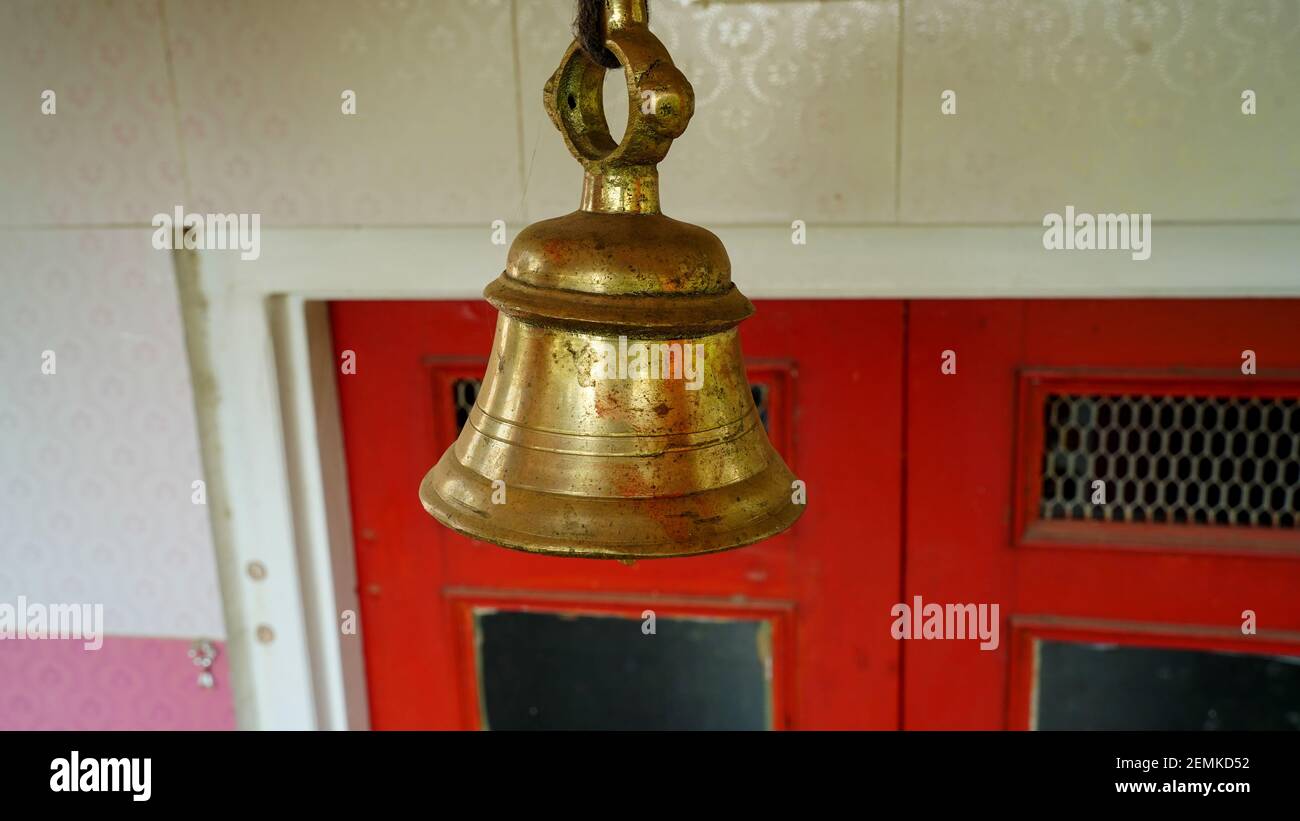 Nouvelle cloche en bronze dans le temple indien isolé sur fond flou. Gros plan d'une cloche en laiton de temple hindou suspendue en or Banque D'Images