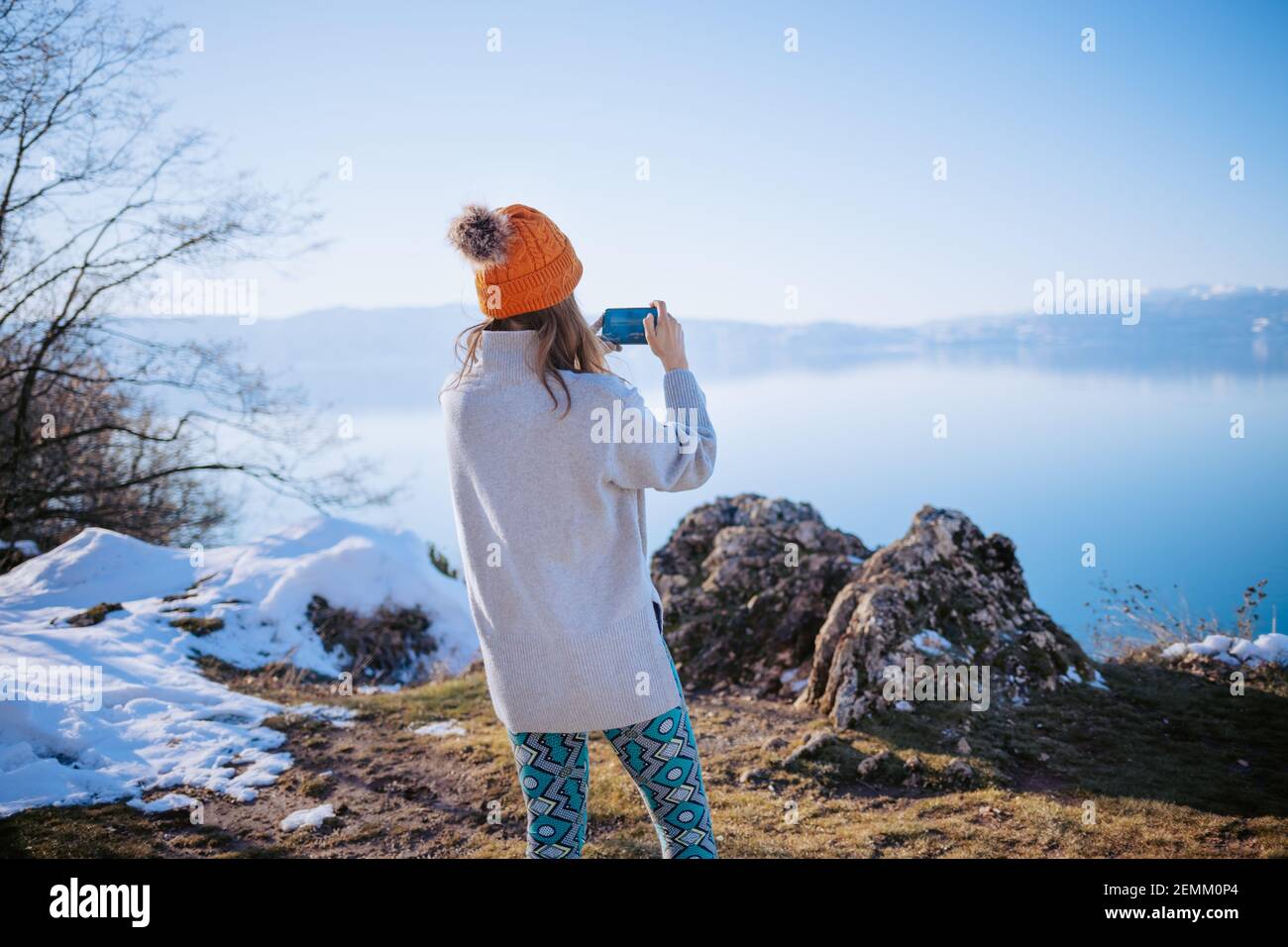 Jeune femme prenant des photos du lac en hiver Banque D'Images