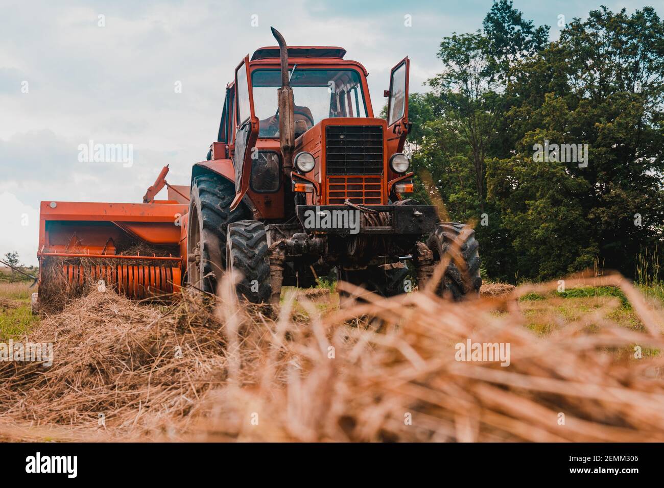 Vieux tracteur rouge dans le champ, champs ukrainiens et machines anciennes, récolte de foin dans le champ.2021 Banque D'Images