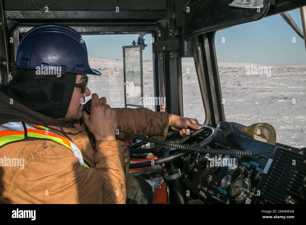 Chauffeur de camion autochtone travaillant pendant la construction hivernale de la route Inuvik-Tuktoyaktuk, dans les Territoires du Nord-Ouest, dans l'ouest de l'Arctique canadien. Banque D'Images