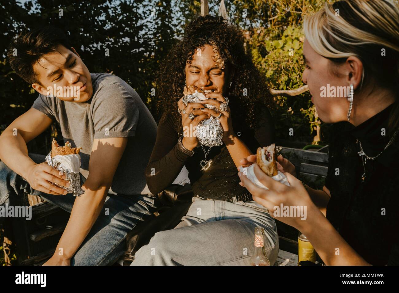 Jeune femme mangeant de la nourriture avec des amis dans le parc Banque D'Images