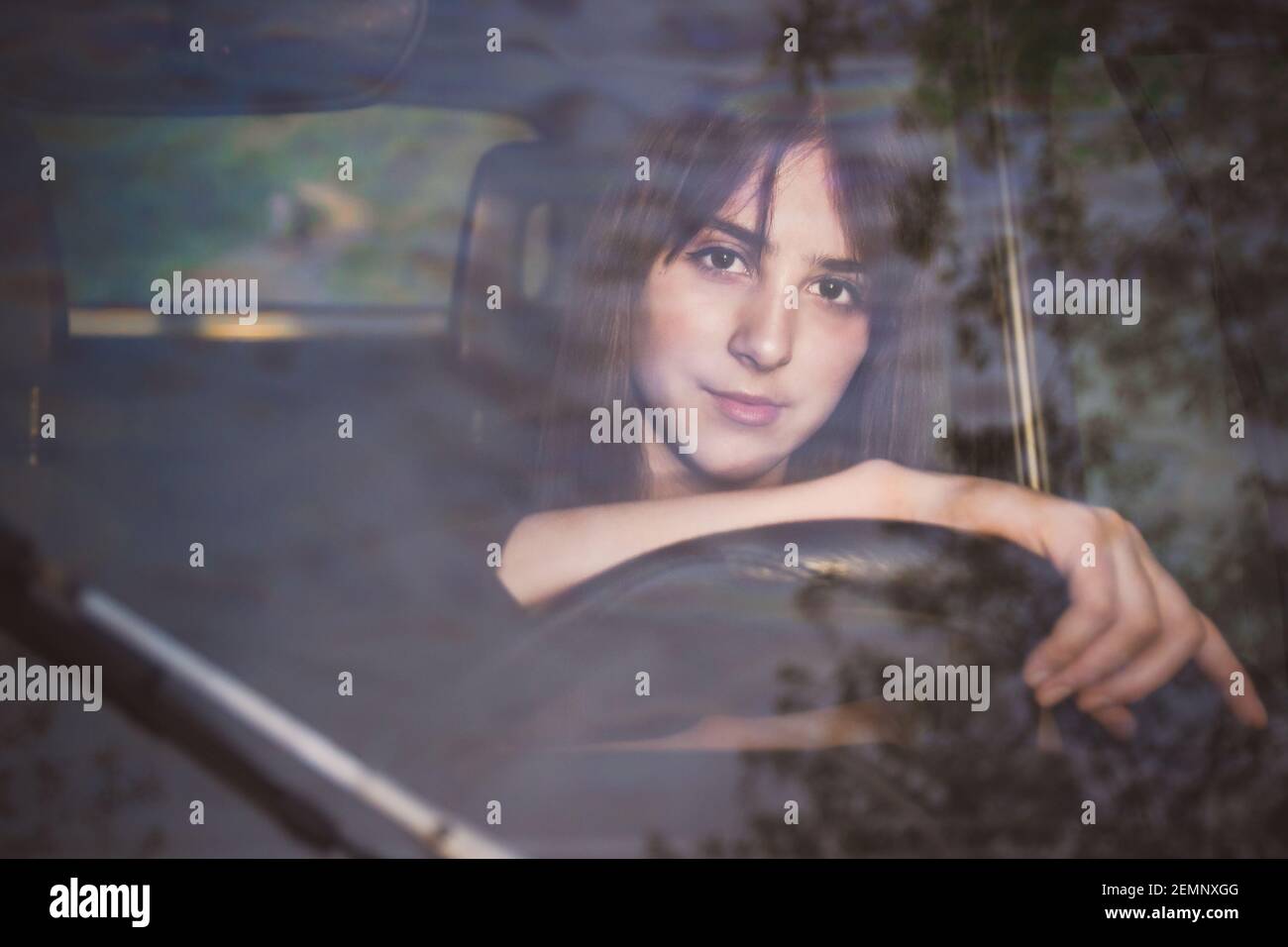 Photo d'une jeune fille brune sur le siège du conducteur. Vue par le pare-brise Banque D'Images