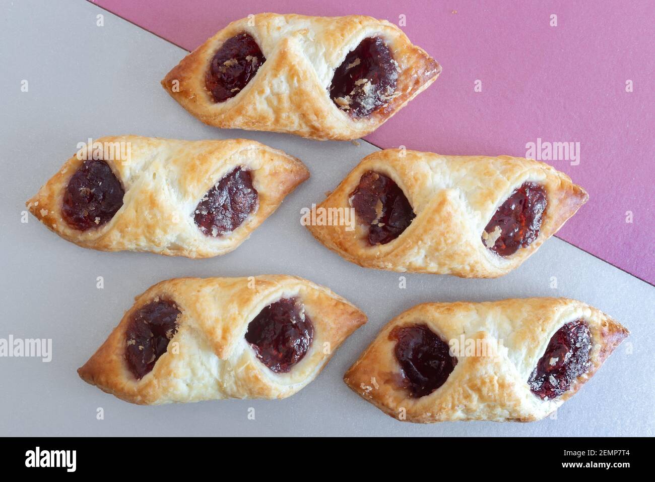 Sur un fond bicolore, une délicieuse pâte feuilletée farcie de confiture de framboises. Vue de dessus avec espace de copie. Gros plan. Banque D'Images