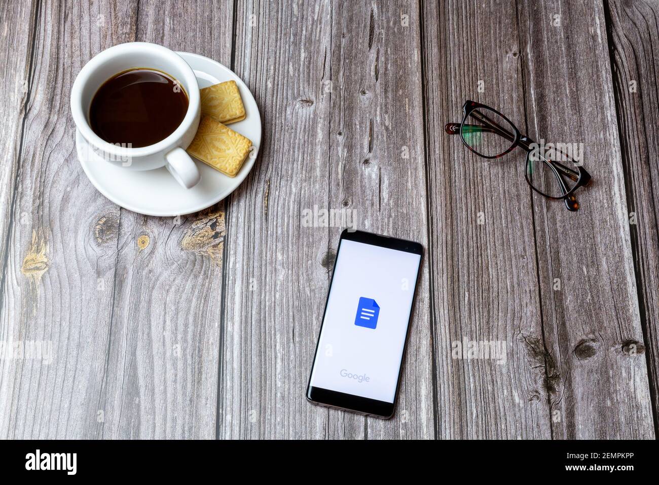 Un téléphone portable ou un téléphone portable sur une table en bois Avec l'application Google Docs ouverte à côté d'un café et lunettes Banque D'Images