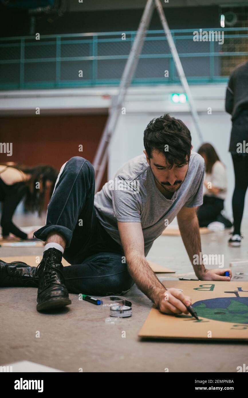 Jeune activiste masculin préparant un panneau pour les questions environnementales Banque D'Images