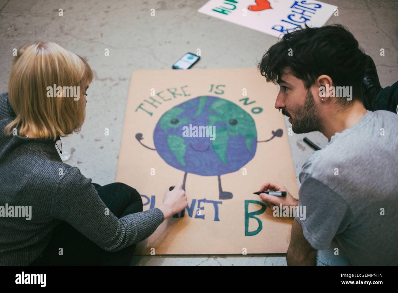 Un jeune manifestant, homme et femme, prépare une affiche pour les questions environnementales Banque D'Images