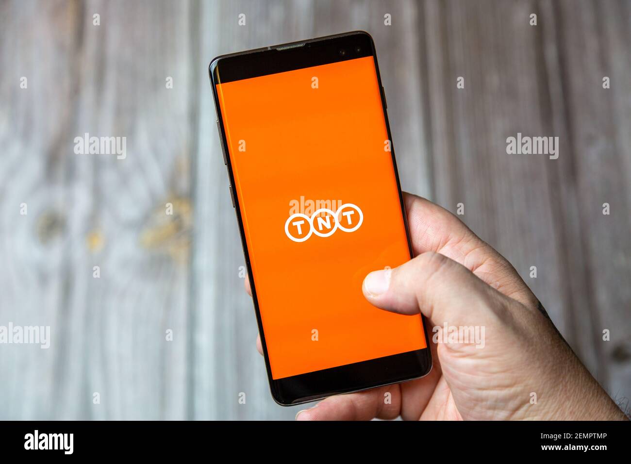 Un téléphone mobile ou mobile détenu par un Main avec l'application de livraison TNT ouverte à l'écran Banque D'Images