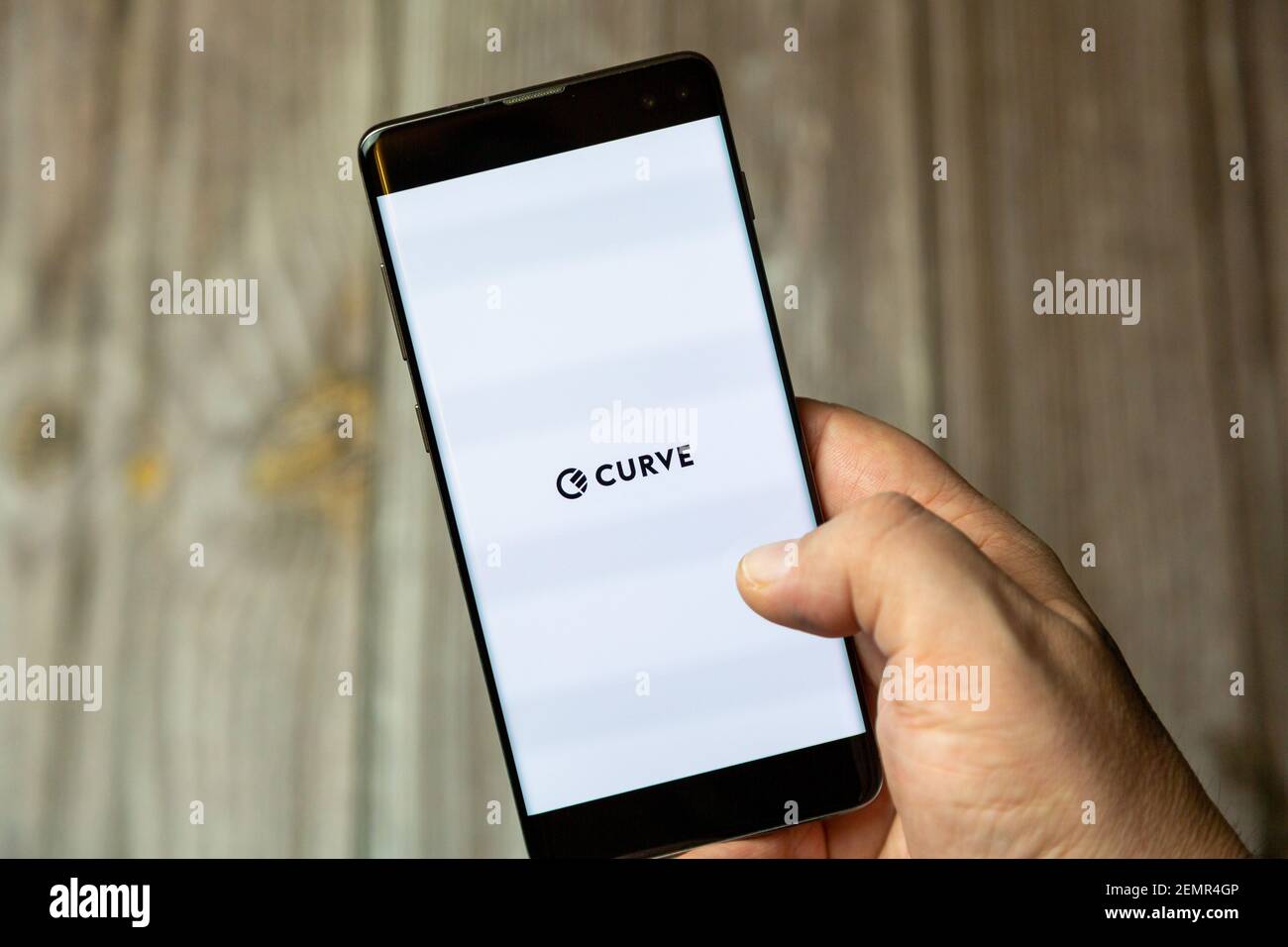 Un téléphone mobile ou mobile détenu par un Main avec l'application Curve ouverte à l'écran Banque D'Images