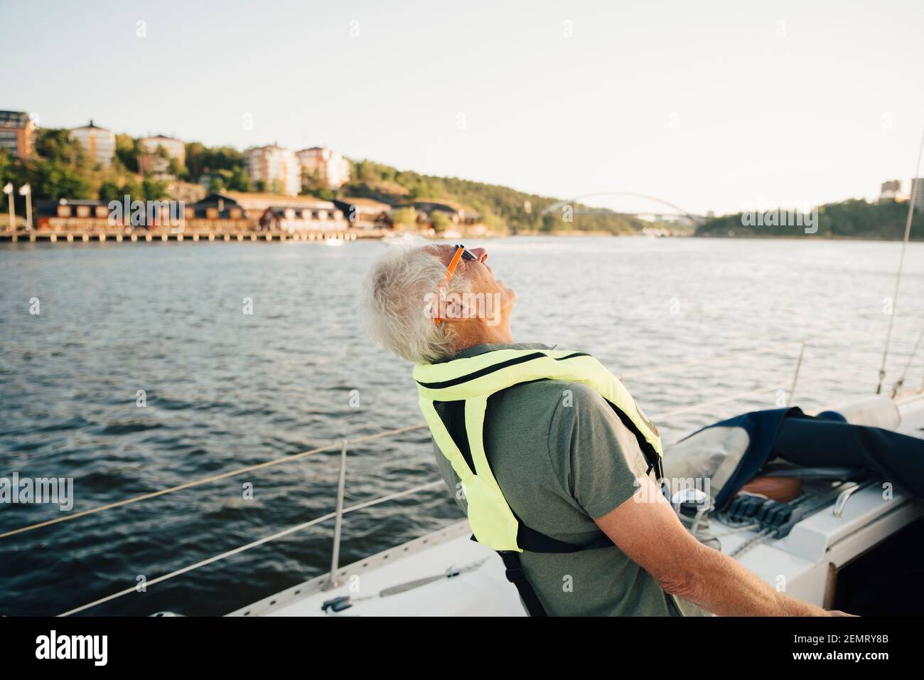Un homme senior riant en bateau contre le ciel le jour ensoleillé Banque D'Images