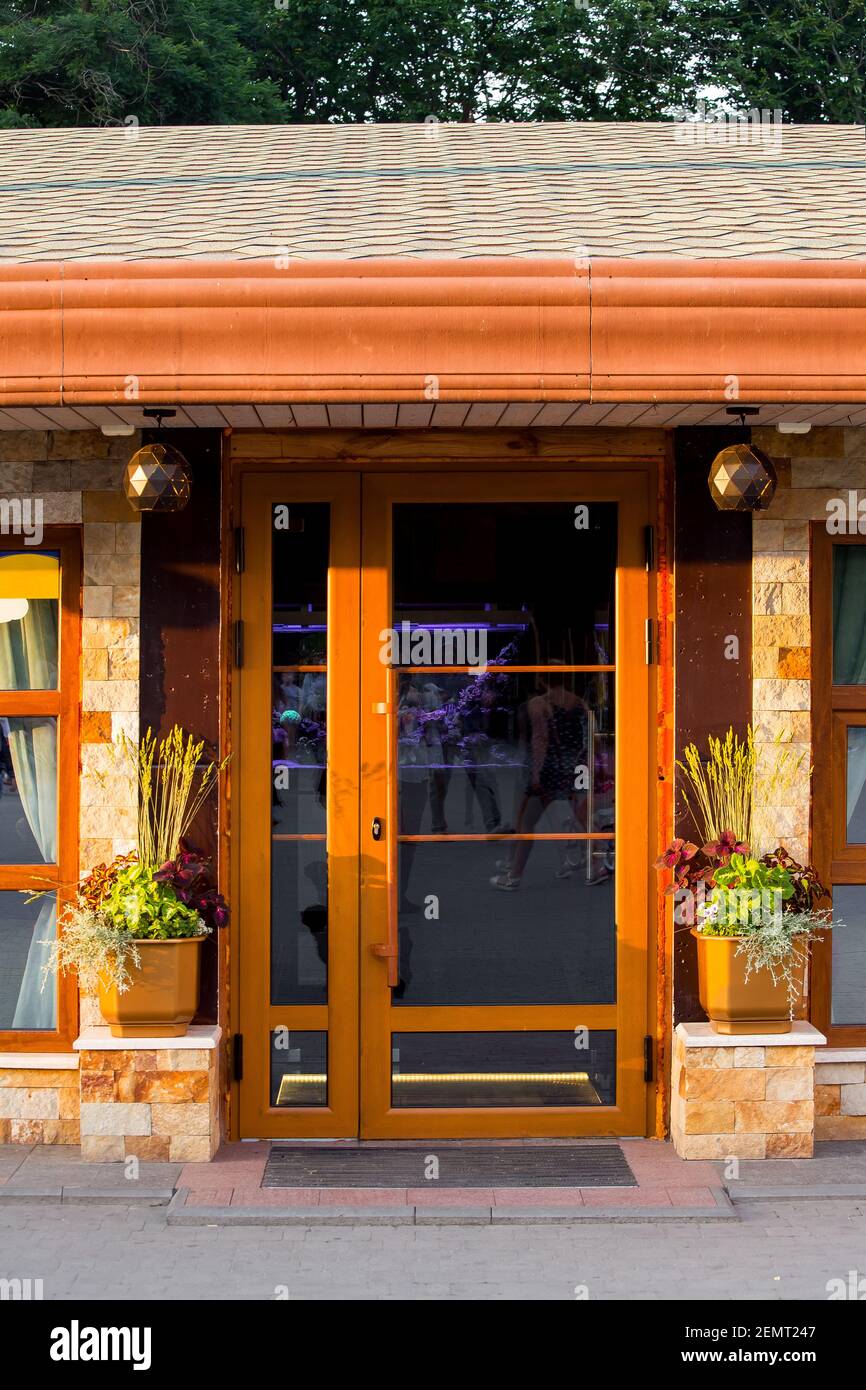 porte marron avec poignée et insert en verre la façade du bâtiment en  carreaux de pierre avec fleur vases et une entrée avec un tapis de pied  sous un can Photo Stock -