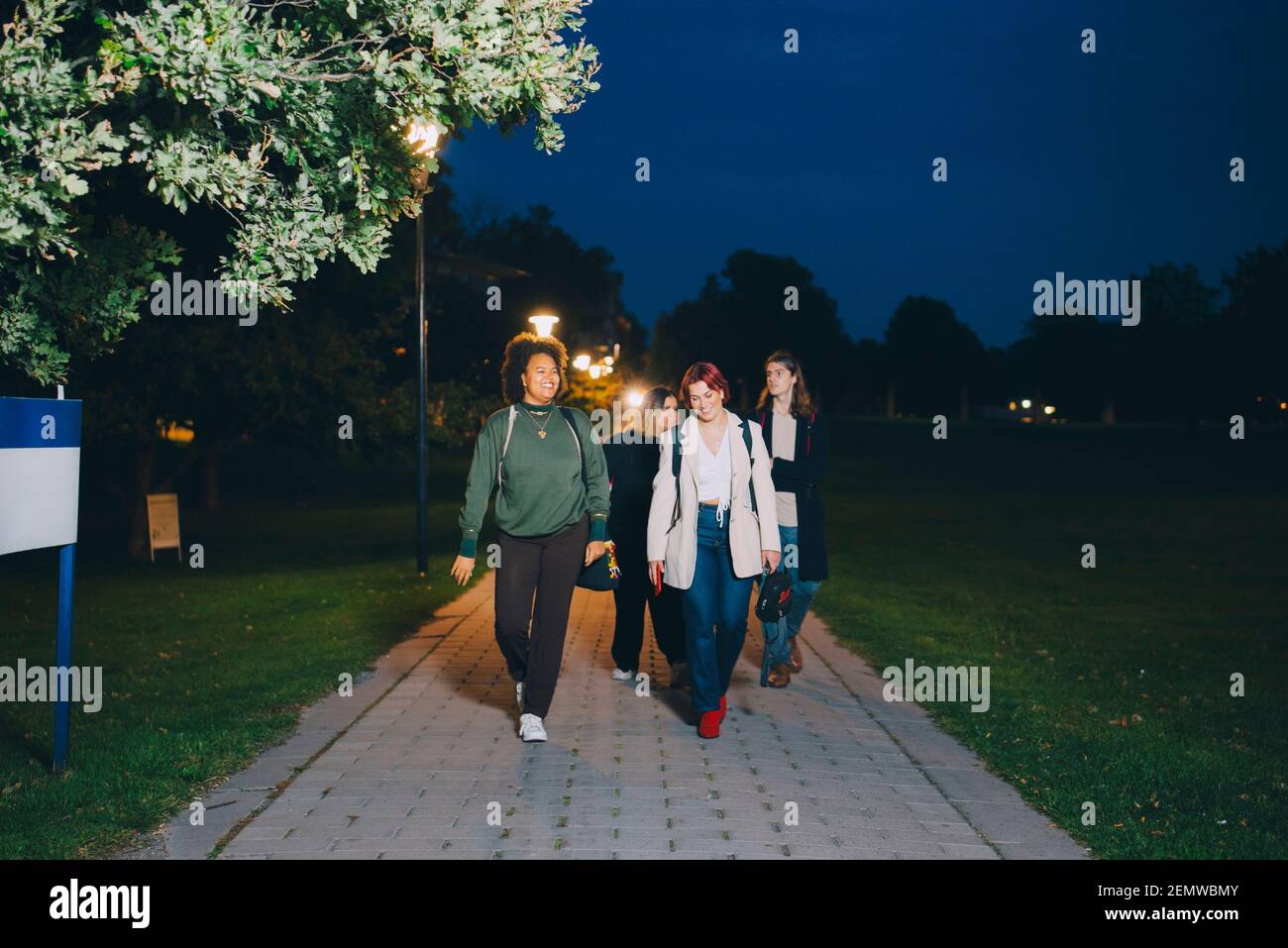 Des amis hommes et femmes heureux marchant sur le campus la nuit Banque D'Images