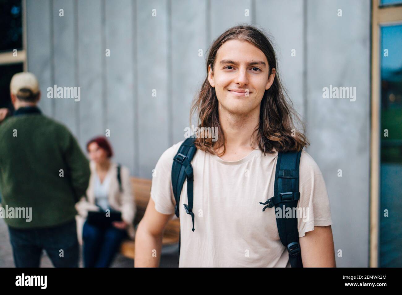 Portrait d'un étudiant souriant contre un mur gris sur le campus Banque D'Images