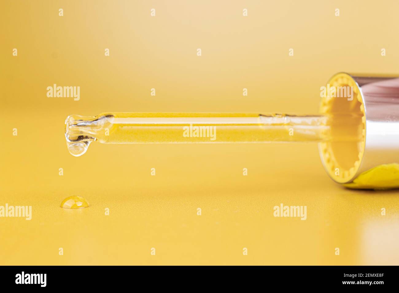 Pipette cosmétique avec une goutte d'huile cosmétique ou de sérum sur fond jaune. Gros plan. Banque D'Images