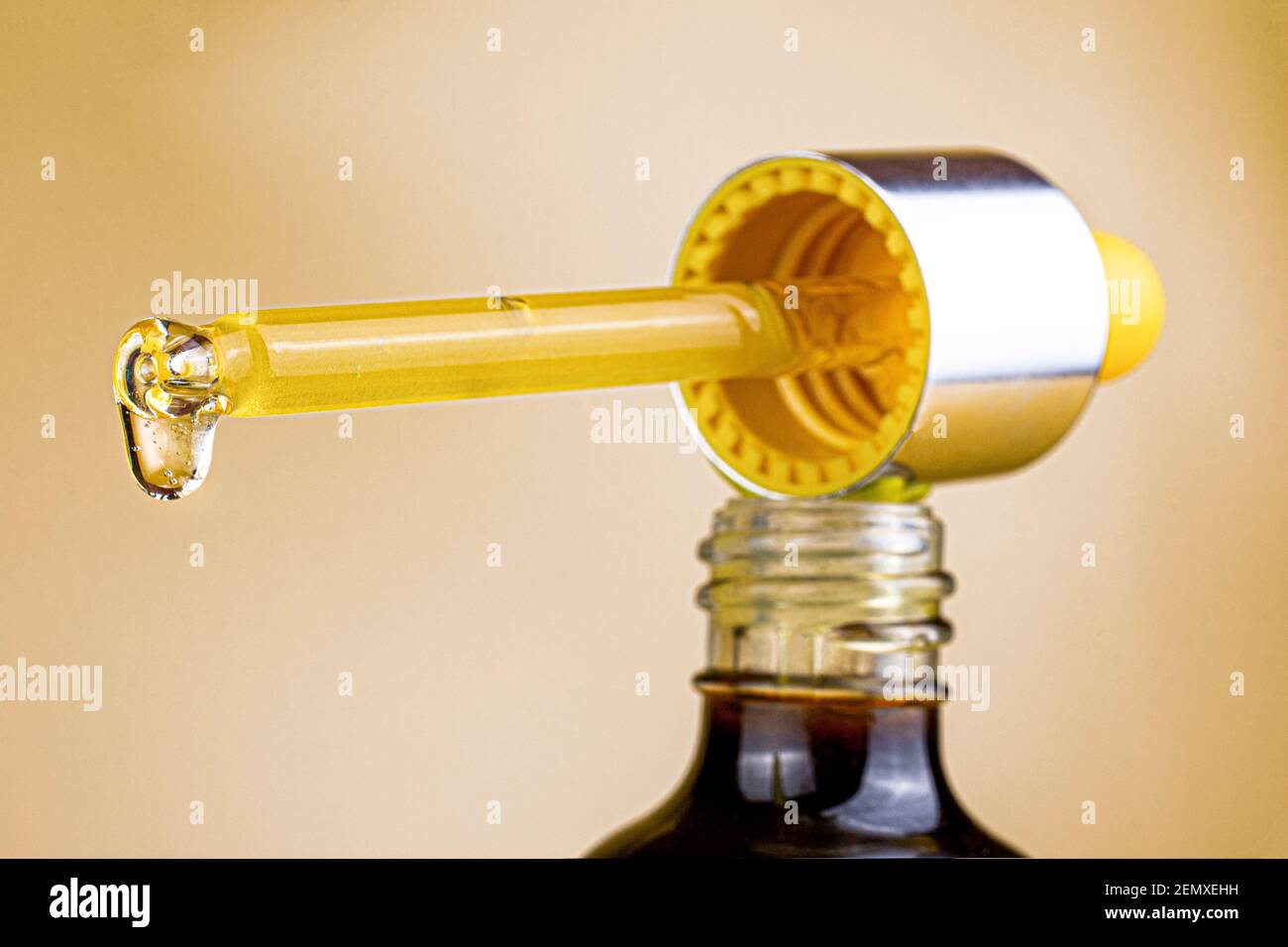 Flacon cosmétique et pipette avec une goutte d'huile cosmétique et de sérum sur une image macro de fond clair. La mise au point sélective se ferme. Banque D'Images